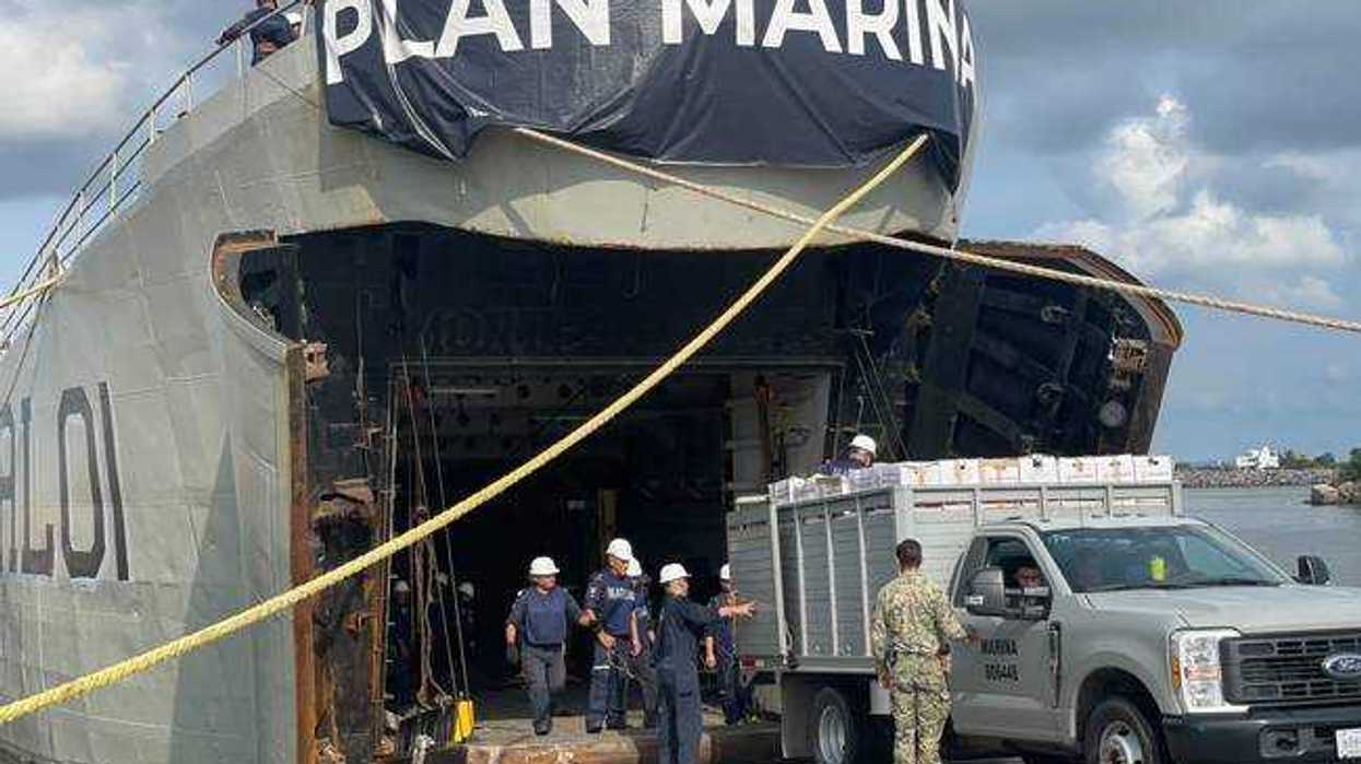 Personal naval con cascos blancos y una camioneta de la Marina junto a la rampa de un buque con la leyenda Plan Marina, en el envío de ayuda por el huracán Polo