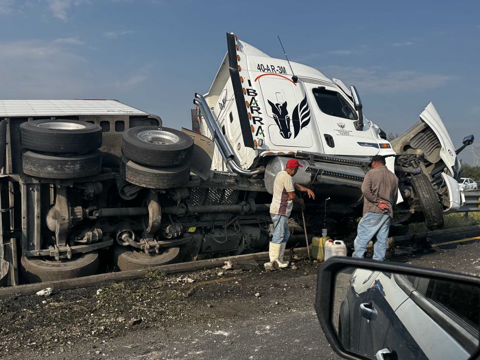 Personas observan el tractocami\u00f3n volcado mientras contin\u00faan las labores para retirar la unidad de la carretera Celaya\u2013Salamanca.