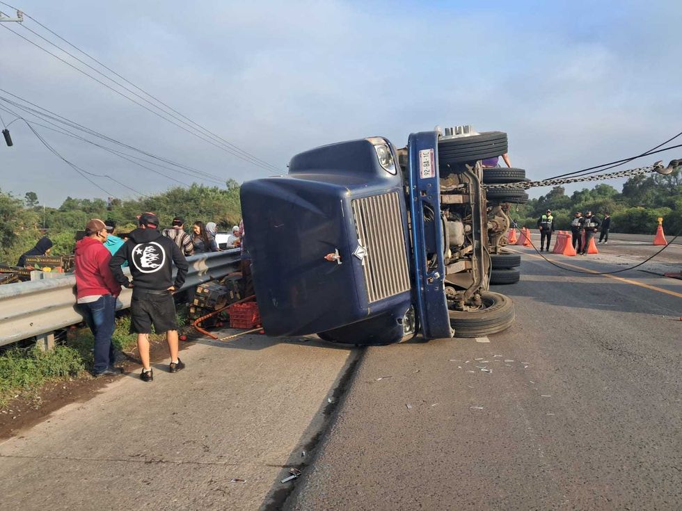 Personas recogen cajas de jitomate junto a un cami\u00f3n volcado en la autopista M\u00e9xico-Quer\u00e9taro.