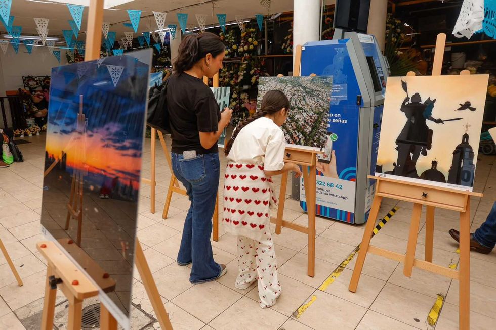 Personas recorren la exposici\u00f3n de fotograf\u00eda instalada entre los locales de un mercado municipal de Quer\u00e9taro.