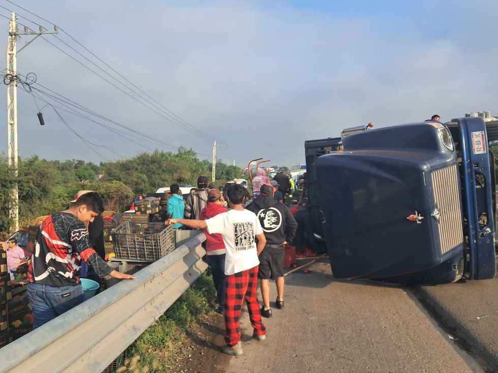 Personas retiran cajas de jitomate tras la volcadura de un cami\u00f3n de carga en la M\u00e9xico-Quer\u00e9taro.
