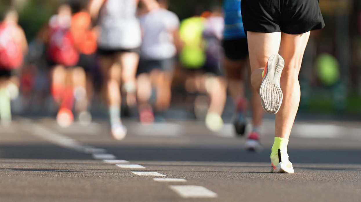 Piernas y calzado deportivo de un grupo de corredores durante una carrera en pavimento