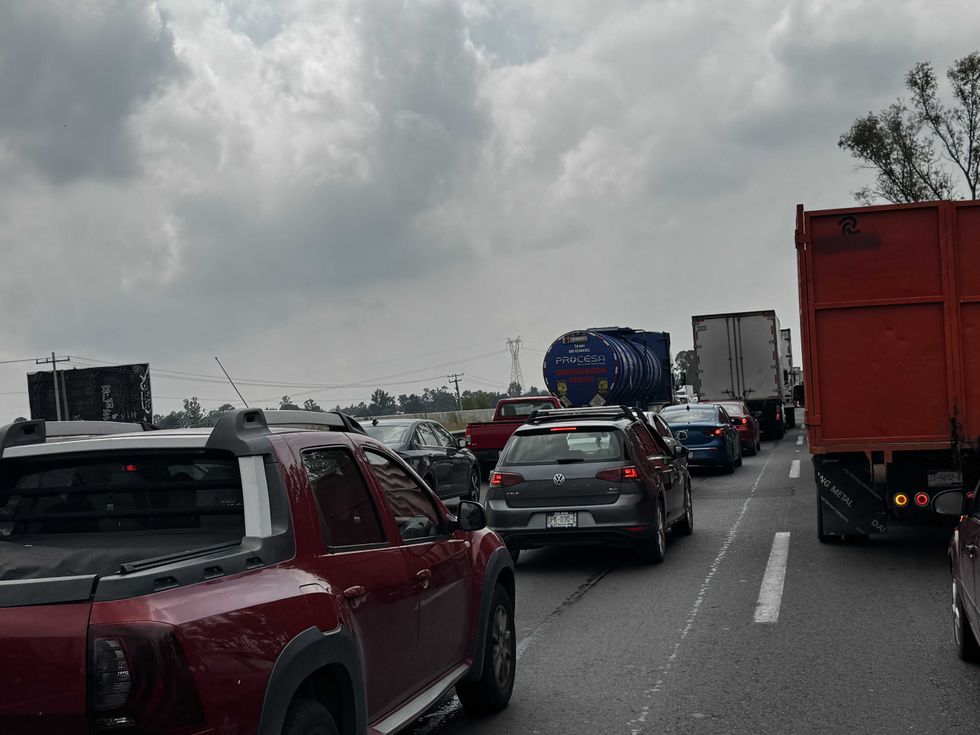 Plano cerrado entre tractocamiones con luces de alerta encendidas detenidos en la autopista M\u00e9xico-Quer\u00e9taro durante el embotellamiento en el tramo de Palmillas, agosto de 2026.