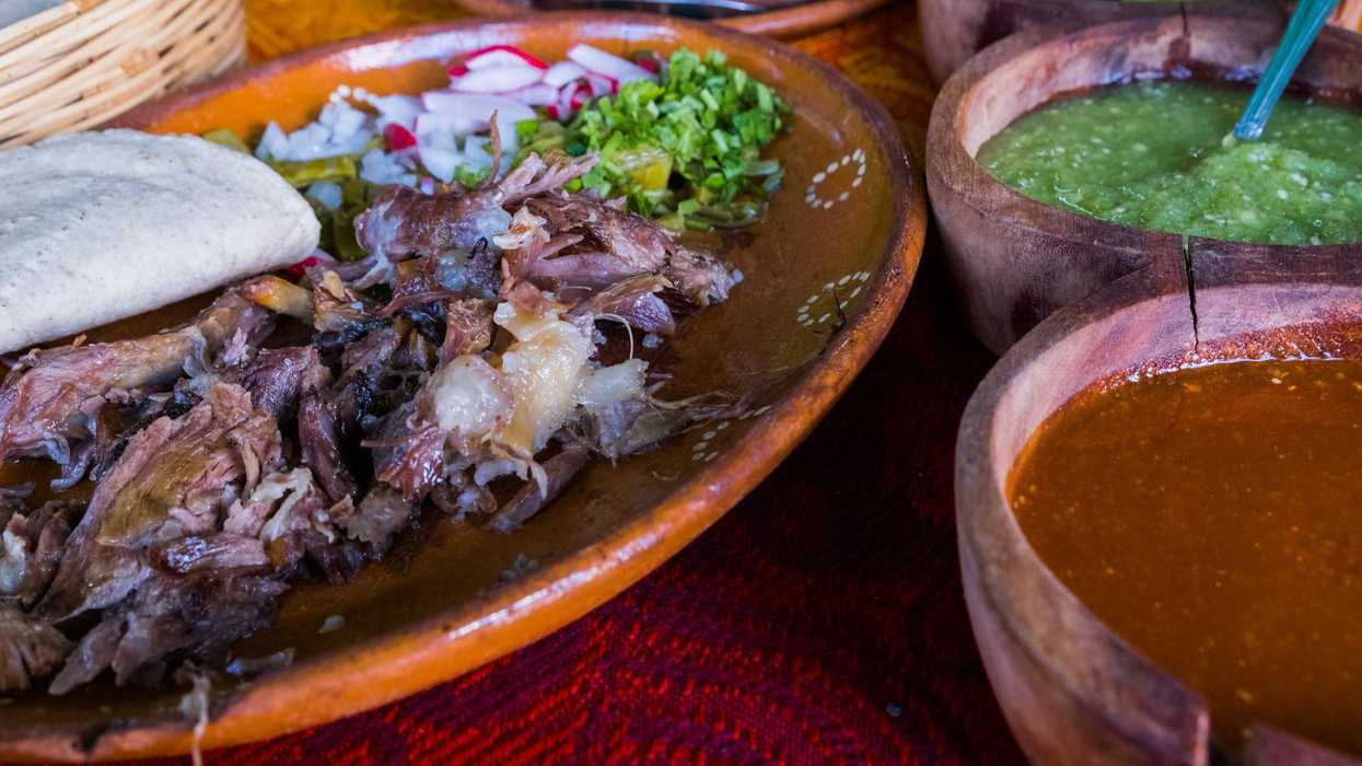 Plato de barro con carne deshebrada, tortilla, cebolla, cilantro y rábano junto a cuencos de madera con salsa verde y salsa roja, parte de la comida tradicional del festival de La Valla.