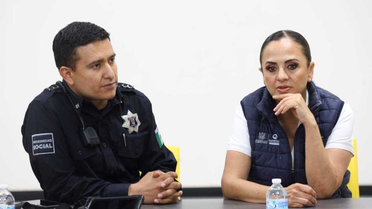 Policía uniformado y funcionaria estatal sentados a una mesa durante la reunión con taxistas en San Juan del Río