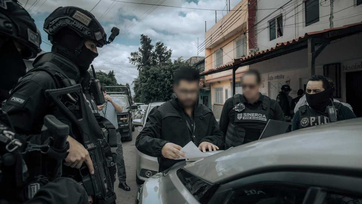 Policías de la POES y agentes de la PID revisan una orden sobre un vehículo en los cateos de Lomas de Casa Blanca