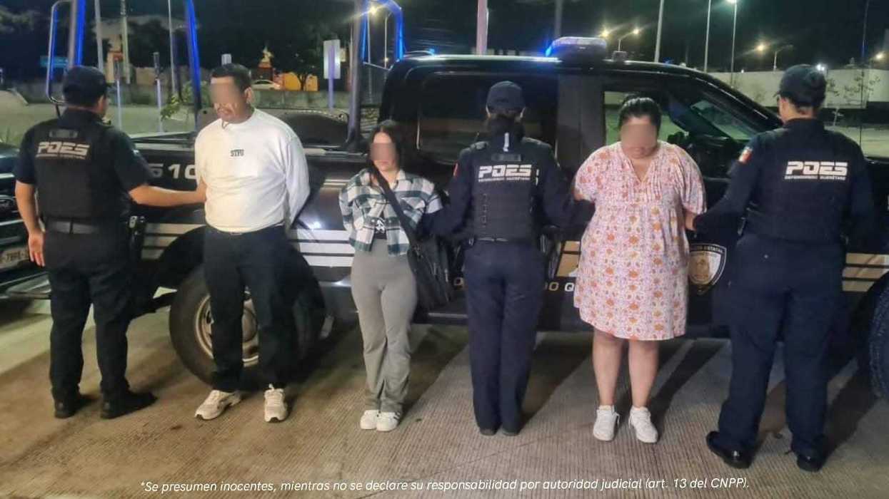 Policías estatales custodian a tres personas detenidas junto a una patrulla en Querétaro