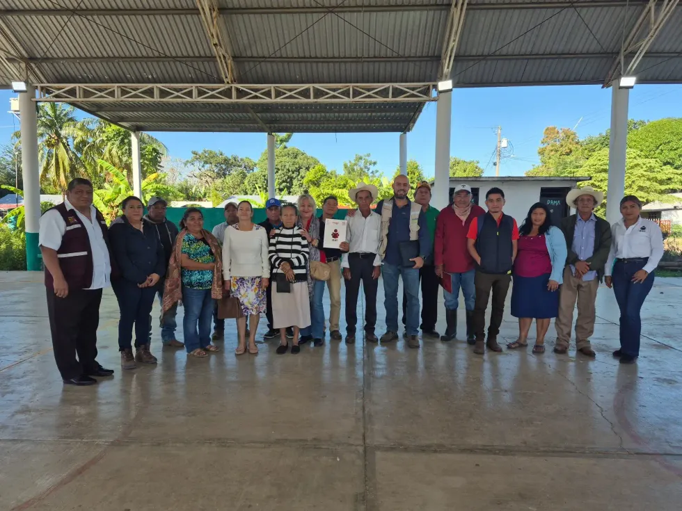 Productores y personal educativo posan con materiales de estudio en una comunidad rural