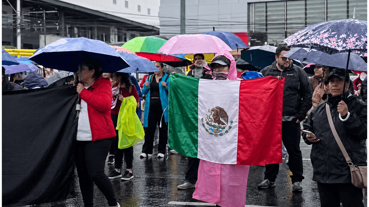 Protesta de trabajadores del IMSS en Querétaro: manifestantes con paraguas, bandera de México y manta negra bajo la lluvia