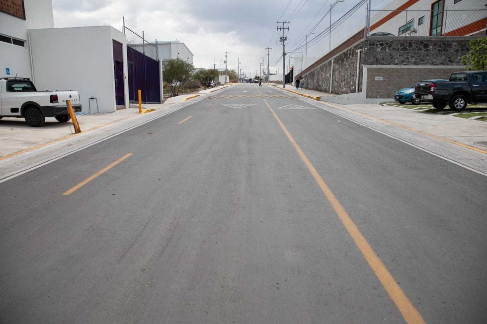 Rehabilitaci\u00f3n de calle Aztecas en Nuevo Parque Industrial de San Juan del R\u00edo, con pavimento nuevo y banquetas reconstruidas en zona industrial queretana