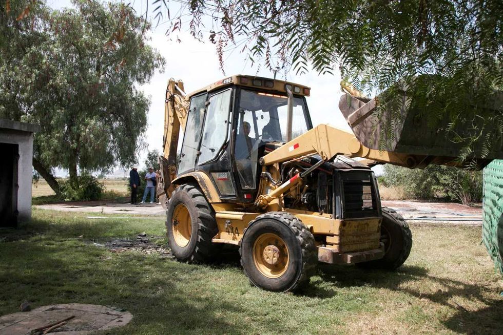 Retroexcavadora amarilla trabaja en un predio con \u00e1rboles y una construcci\u00f3n de tabique durante las obras de la planta de tratamiento de aguas residuales de El Blanco, Col\u00f3n.