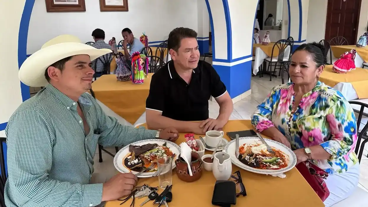 Ricardo Astudillo, al centro, conversa con dos asistentes en torno a una mesa durante un encuentro en un restaurante de la Sierra Gorda.