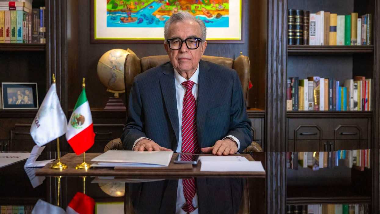 Rubén Rocha Moya sentado frente a un escritorio durante un mensaje, con las banderas de México y Sinaloa a un costado.