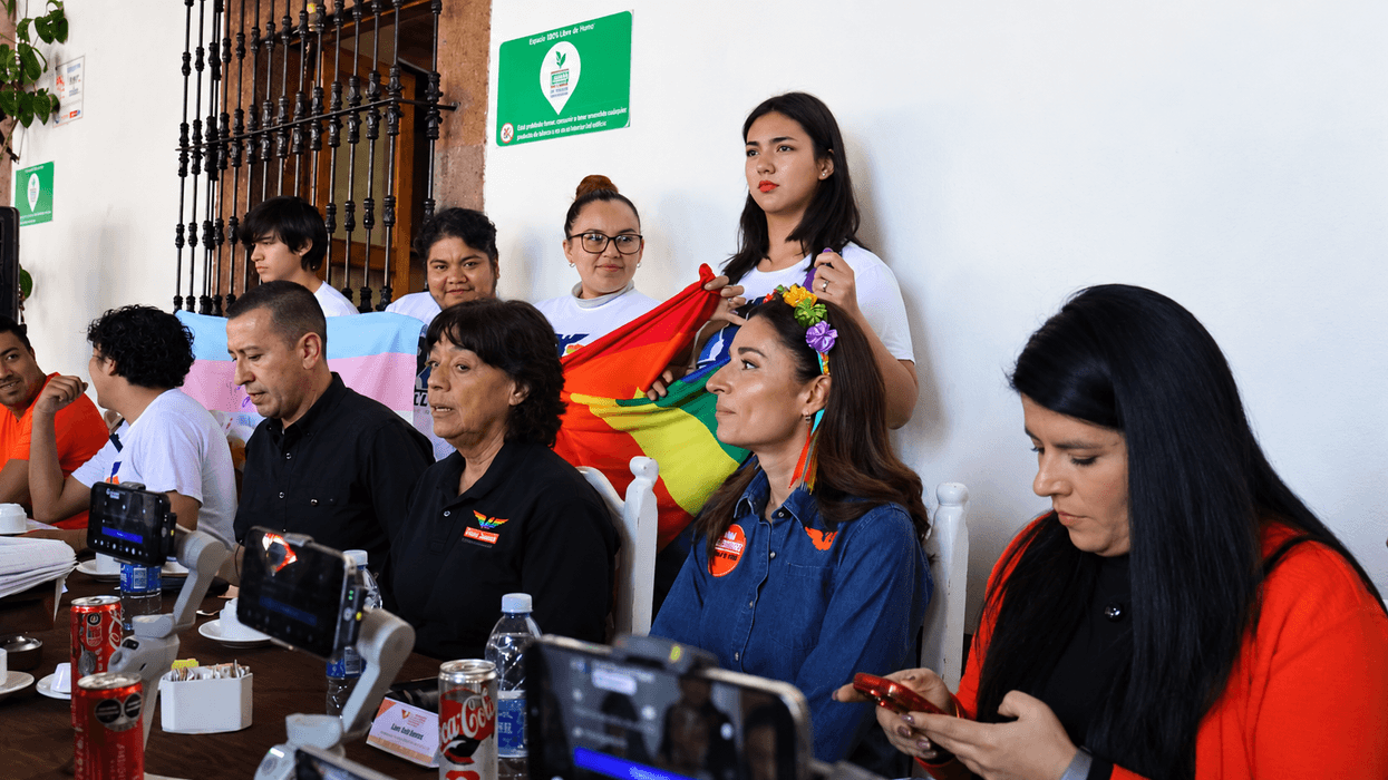Rueda de prensa de Movimiento Ciudadano en San Juan del Río sobre amparos por identidad de género, con integrantes de la comunidad LGBT+ que sostienen la bandera del orgullo y la bandera trans detrás de la mesa.