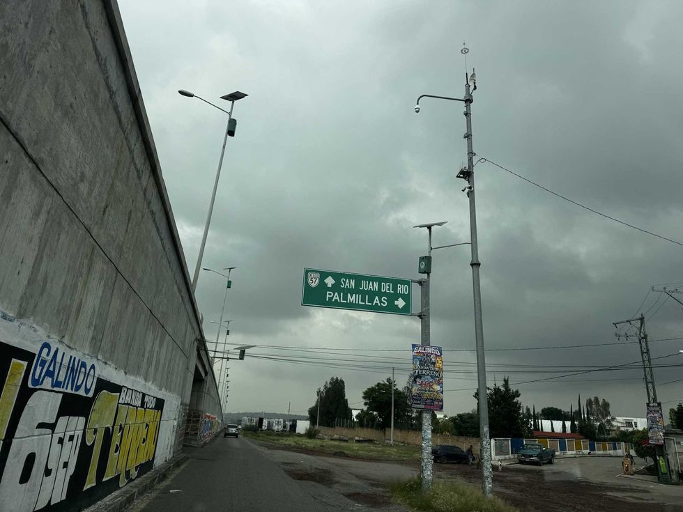 Se\u00f1alamiento verde hacia San Juan del R\u00edo y Palmillas junto al muro del puente elevado