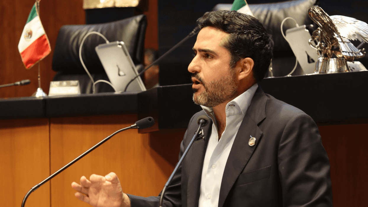Senador Agustín Dorantes, del PAN, habla en un podio con micrófonos; al fondo, bandera de México y escultura de un águila