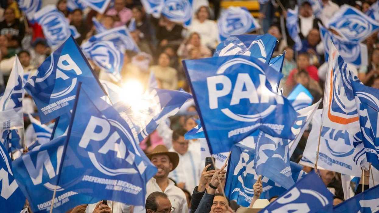 Simpatizantes del PAN agitan banderas azules del partido durante un evento, imagen de la nota sobre las encuestas del PAN en Querétaro para definir nombramientos.