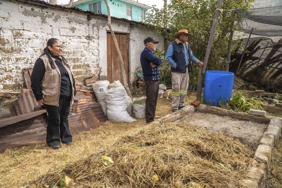 T\u00e9cnica de Agricultura y dos productores observan canal de compostaje en patio rural durante recorrido de Escuela de Campo