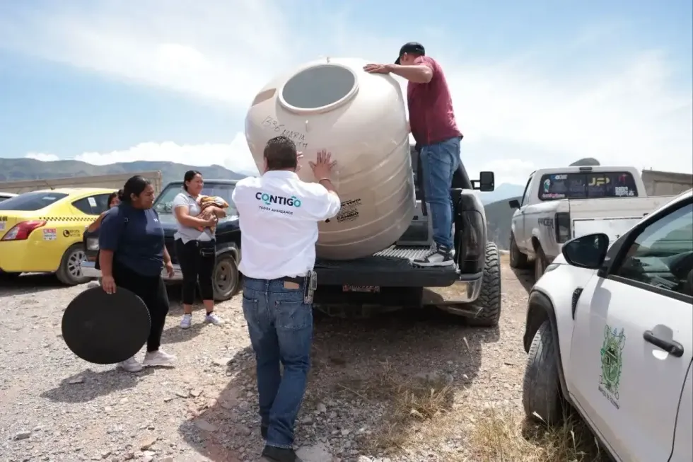 Tinacos y lavadora en camioneta con la sierra de Pe\u00f1amiller al fondo