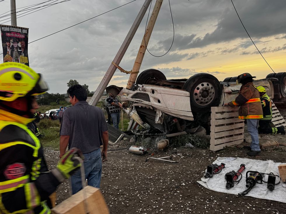 Tr\u00e1iler cargado con cemento volcado sobre la carretera Federal 45, en el acceso a Paso de Mata, donde bomberos realizan labores para rescatar al conductor prensado.