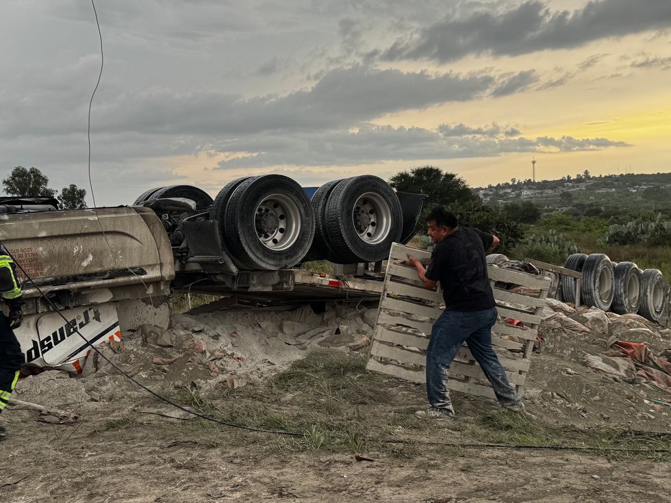 Tr\u00e1iler cargado con cemento volcado sobre la carretera Federal 45, en el acceso a Paso de Mata, donde bomberos realizan labores para rescatar al conductor prensado.