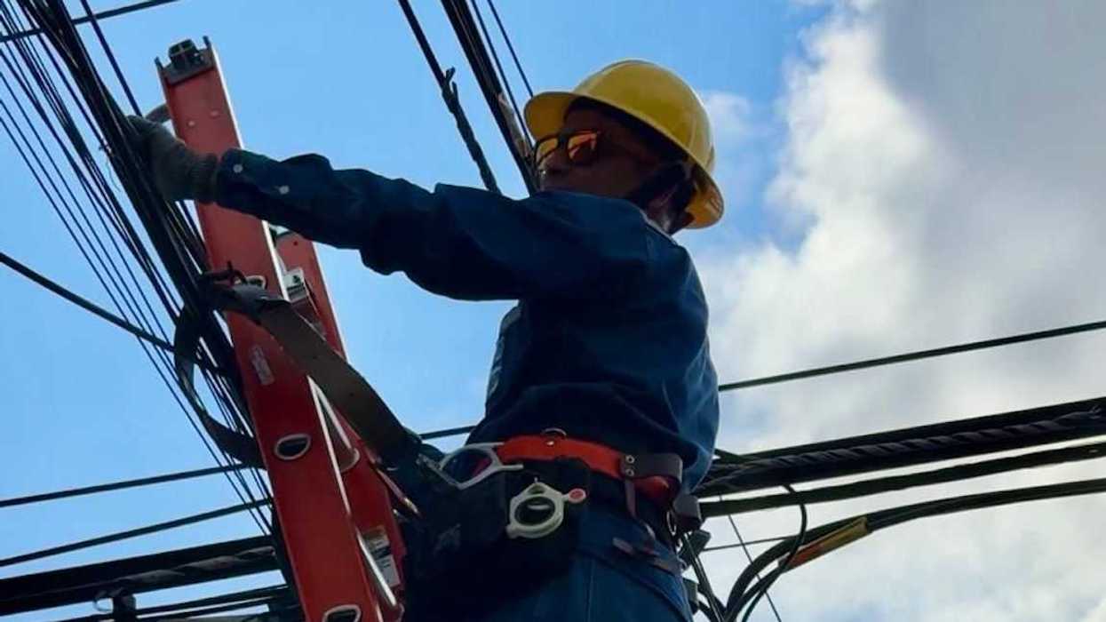 Trabajador con casco amarillo y overol azul interviene cables en poste desde escalera de 7.3 metros en Querétaro