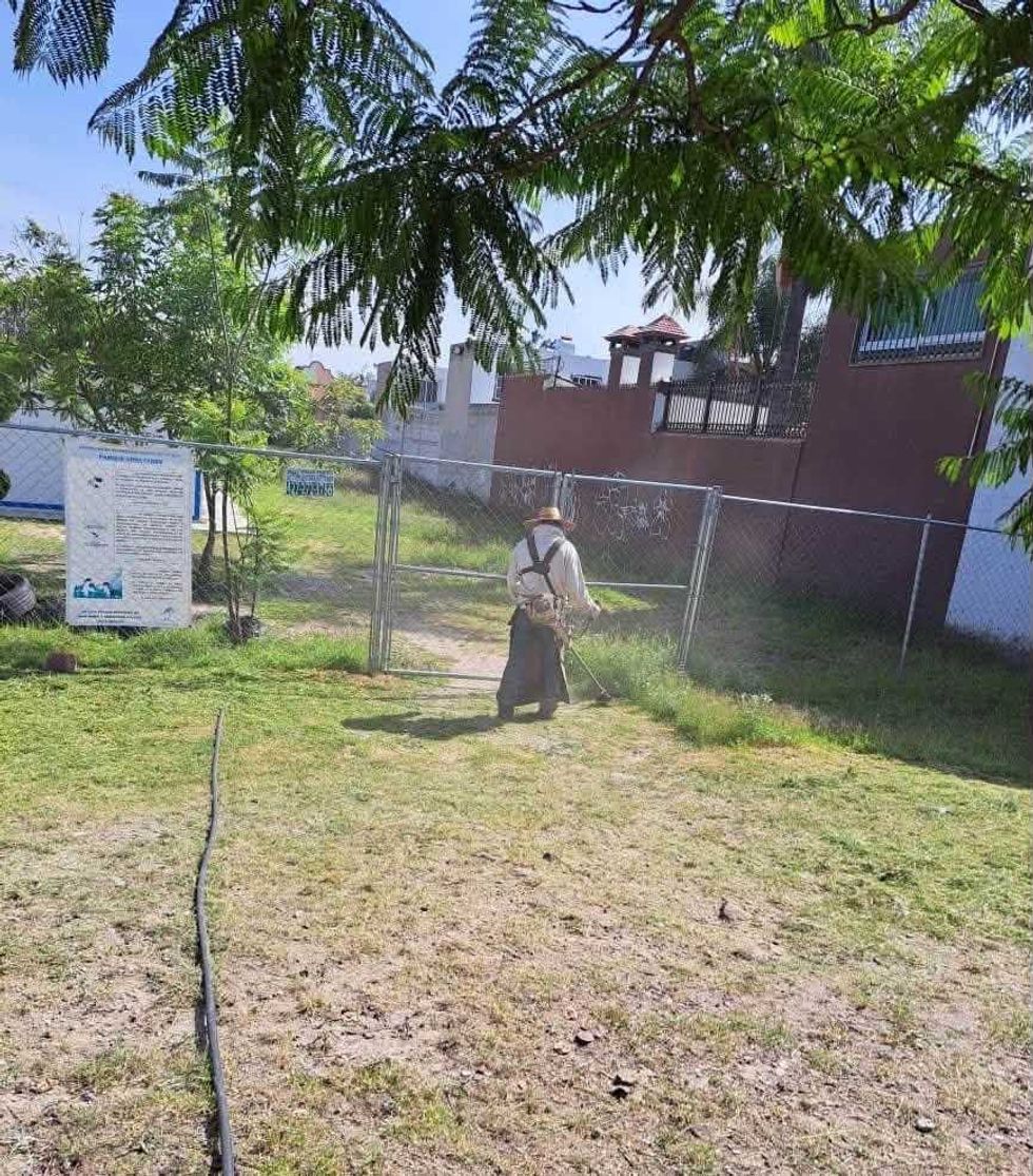 Trabajador con desmalezadora en \u00e1rea verde junto a malla cicl\u00f3nica, parque en San Juan del R\u00edo