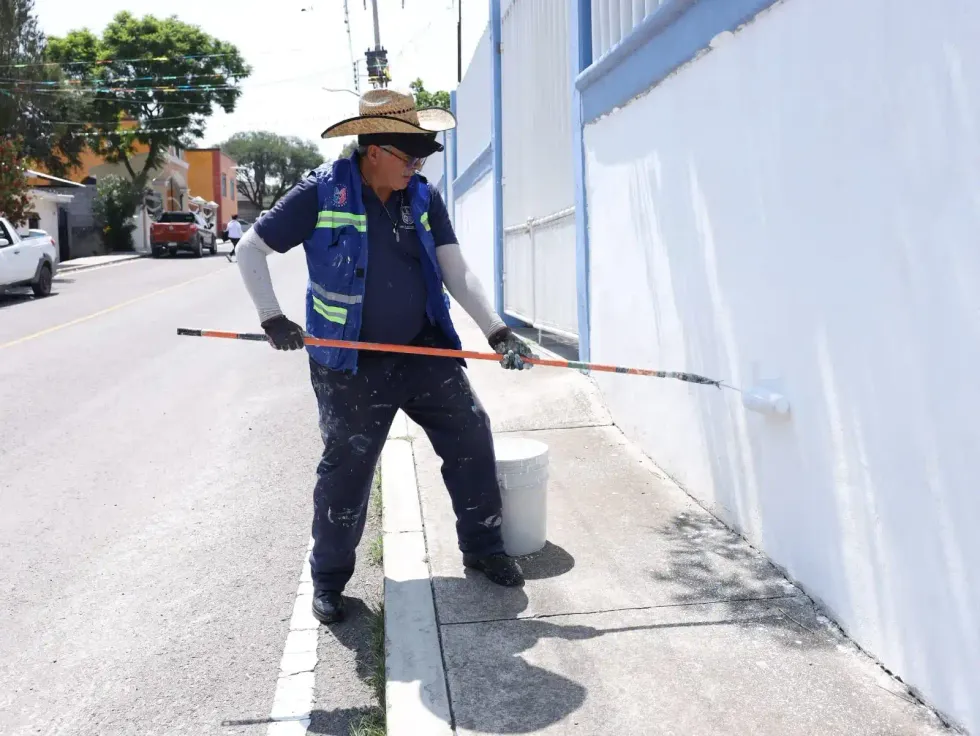 Trabajador de Obras P\u00fablicas del municipio de San Juan del R\u00edo pinta reductores de velocidad en Dolores Godoy durante la edici\u00f3n 52 del programa comunitario itinerante.