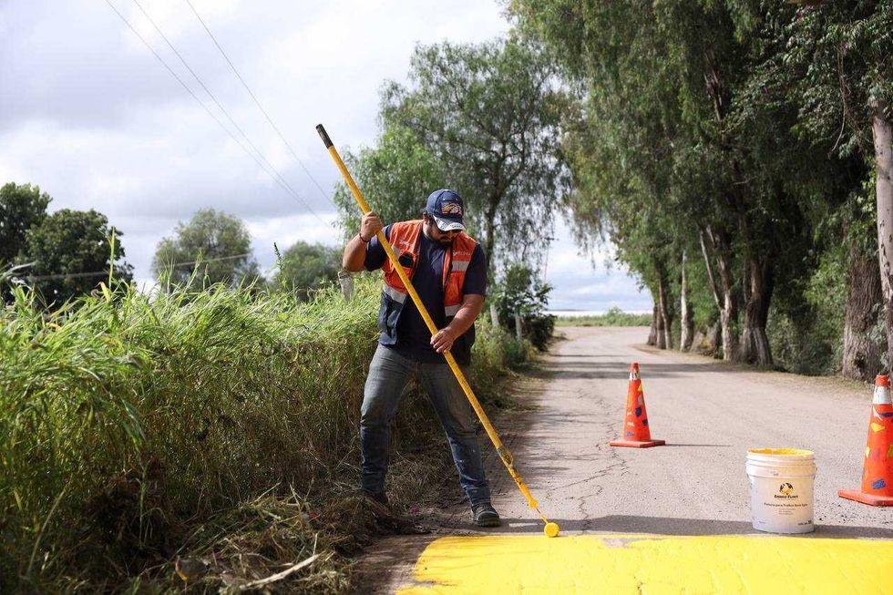 Trabajador de Obras P\u00fablicas pinta un reductor de velocidad en Laguna de Lourdes, San Juan del R\u00edo.