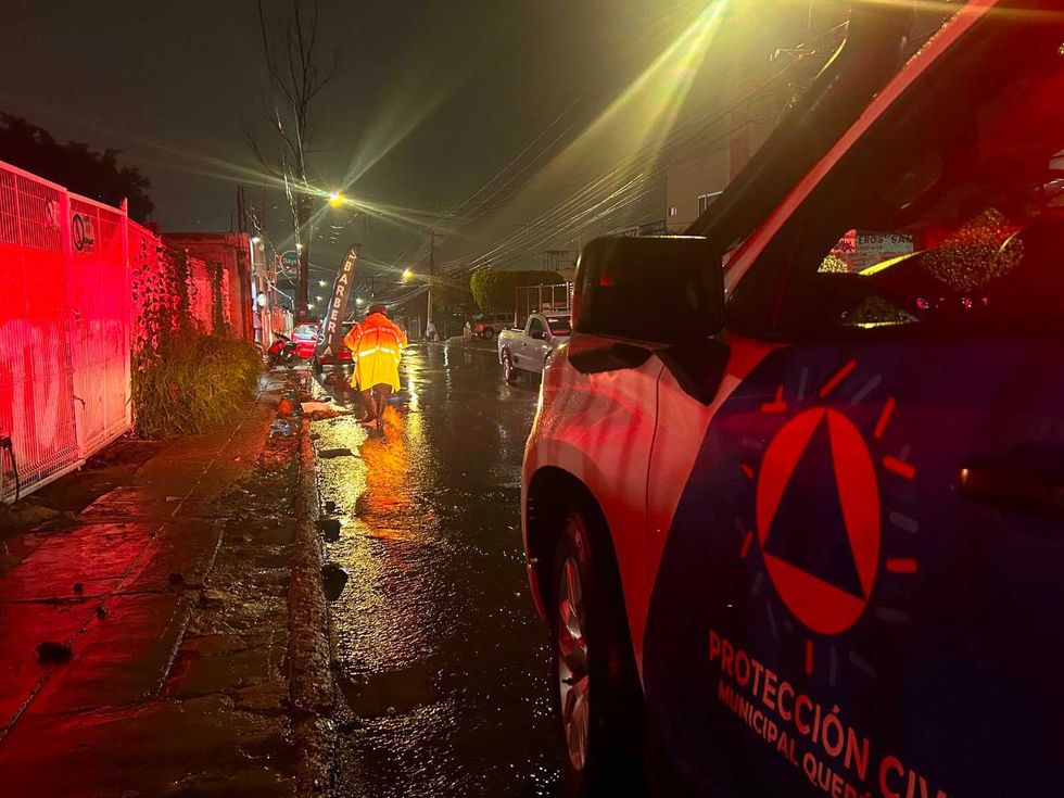Trabajador de Servicios P\u00fablicos Municipales desazolva rejilla pluvial bajo lluvia intensa en vialidad de Quer\u00e9taro la noche del 10 de agosto de 2026