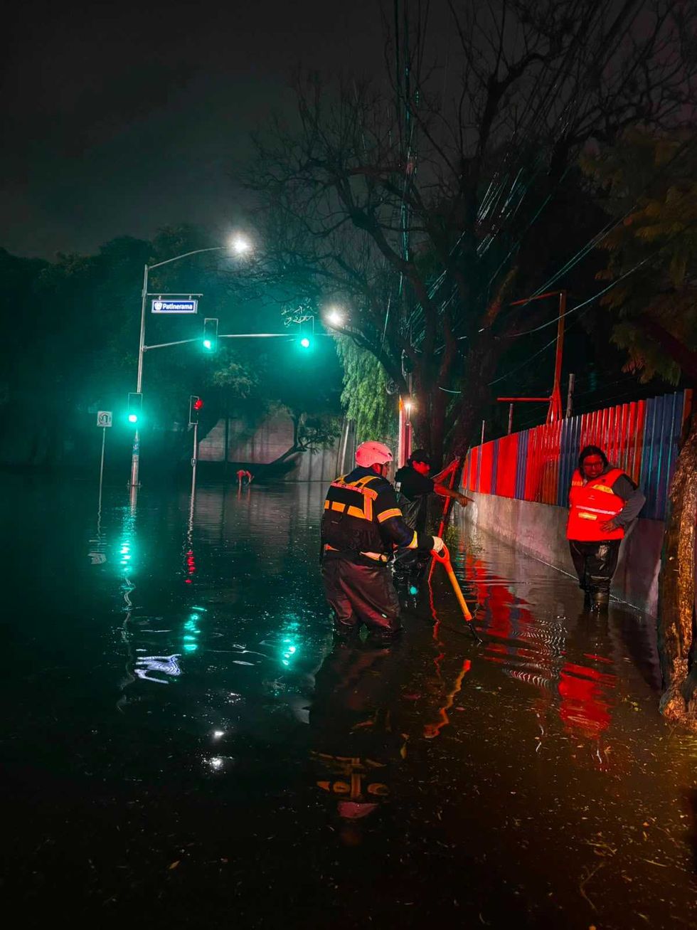 Trabajador de Servicios P\u00fablicos Municipales desazolva rejilla pluvial bajo lluvia intensa en vialidad de Quer\u00e9taro la noche del 10 de agosto de 2026