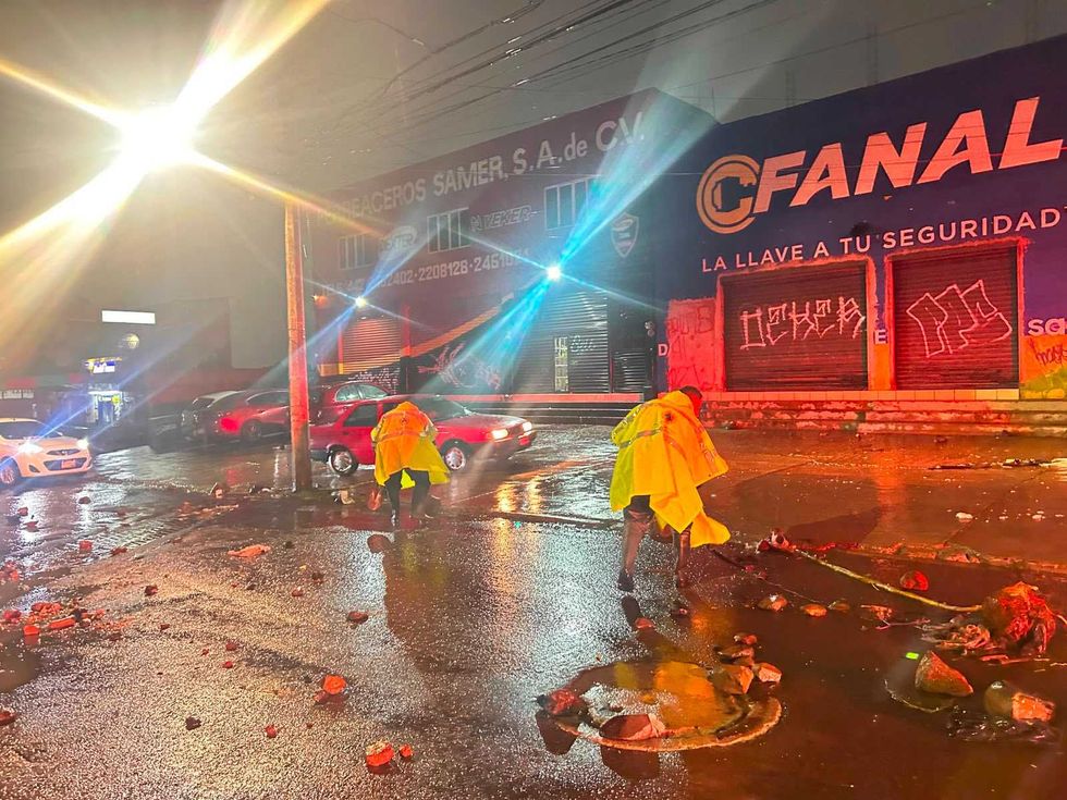 Trabajador de Servicios P\u00fablicos Municipales desazolva rejilla pluvial bajo lluvia intensa en vialidad de Quer\u00e9taro la noche del 10 de agosto de 2026
