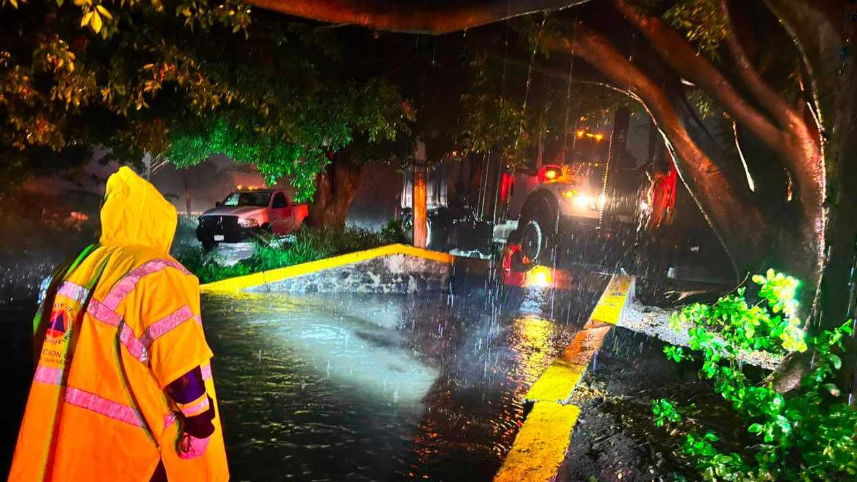 Trabajador de Servicios Públicos Municipales desazolva rejilla pluvial bajo lluvia intensa en vialidad de Querétaro la noche del 10 de agosto de 2026