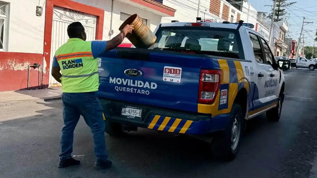Trabajador del Plan Orden coloca una cubeta en la batea de una camioneta de Movilidad Querétaro