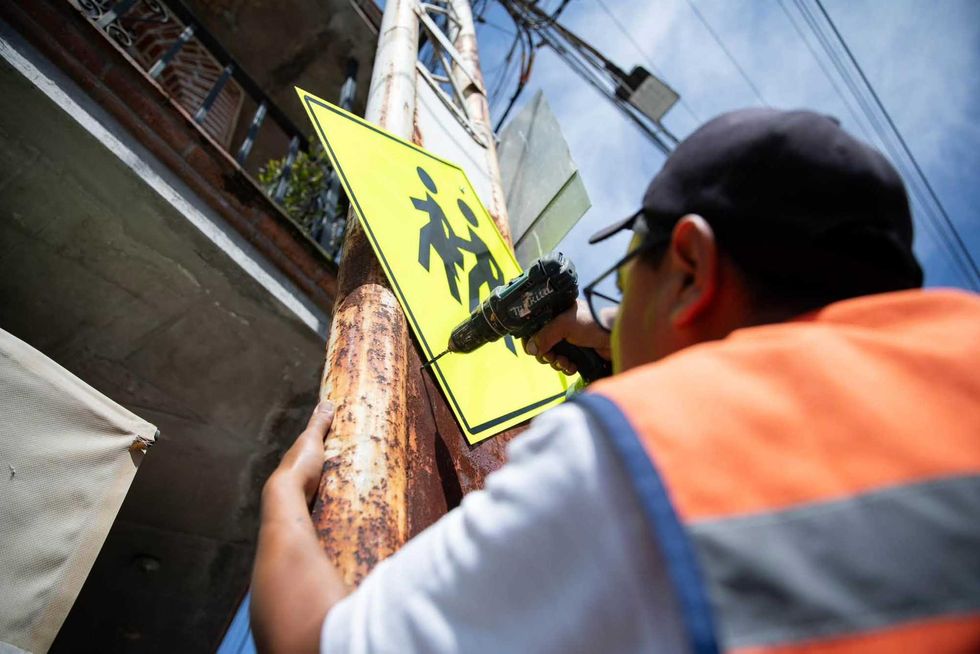 Trabajador instala una se\u00f1al de cruce peatonal como parte de la rehabilitaci\u00f3n de espacios p\u00fablicos en Visth\u00e1, San Juan del R\u00edo.