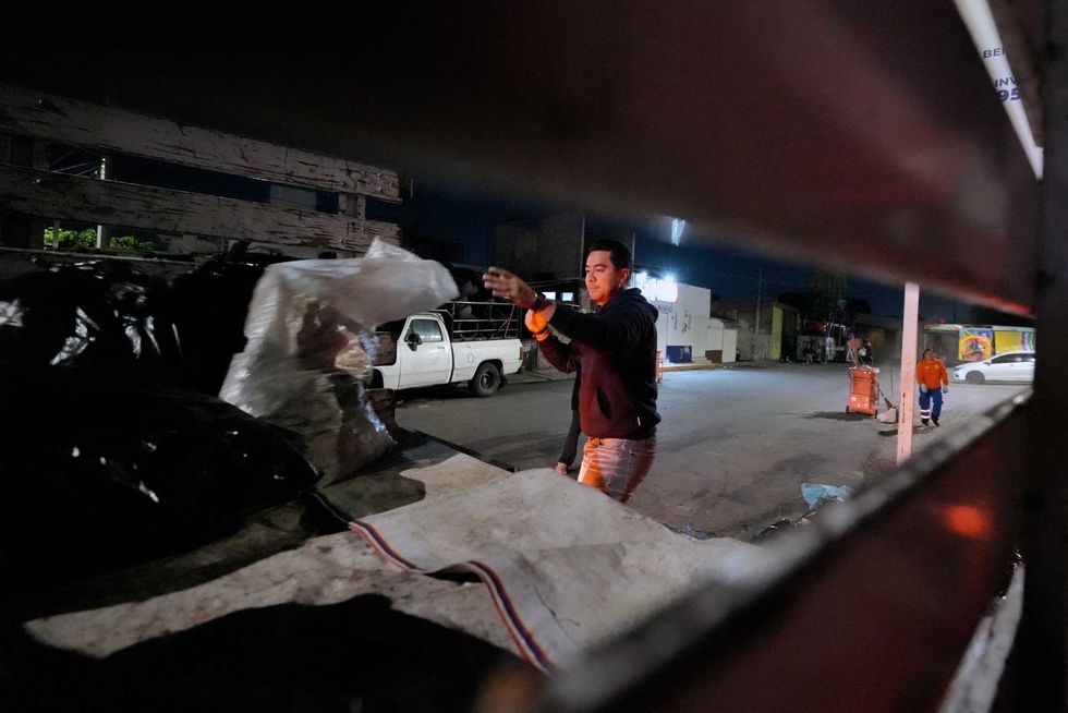 Trabajador lanza bolsa de residuos comerciales a cami\u00f3n recolector durante labores nocturnas en Quer\u00e9taro