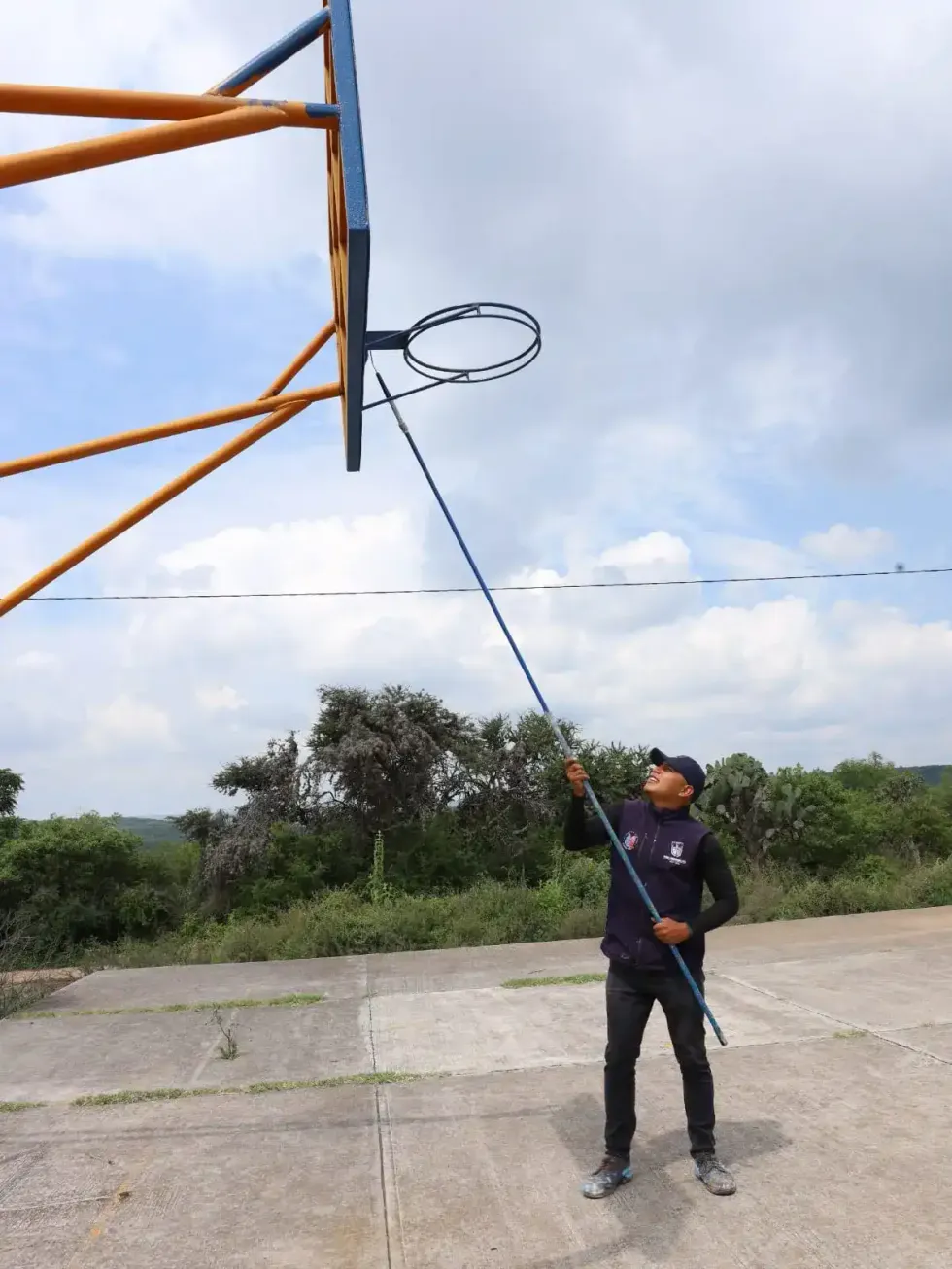 Trabajador municipal con vara pinta aro de cancha de basquetbol en Soledad del R\u00edo