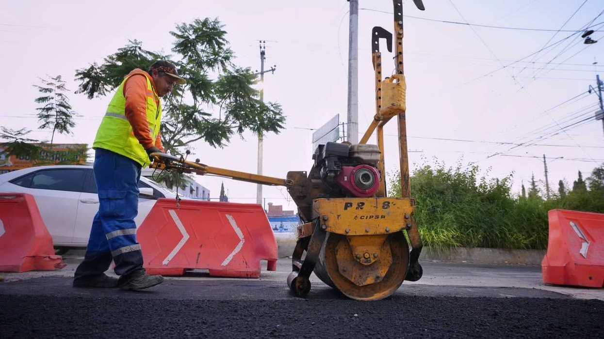 Trabajador opera rodillo compactador sobre asfalto fresco en vialidad municipal de Querétaro durante obras de bacheo