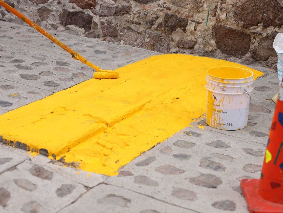 Trabajador pinta de amarillo un reductor de velocidad en una calle de Lomo de Toro