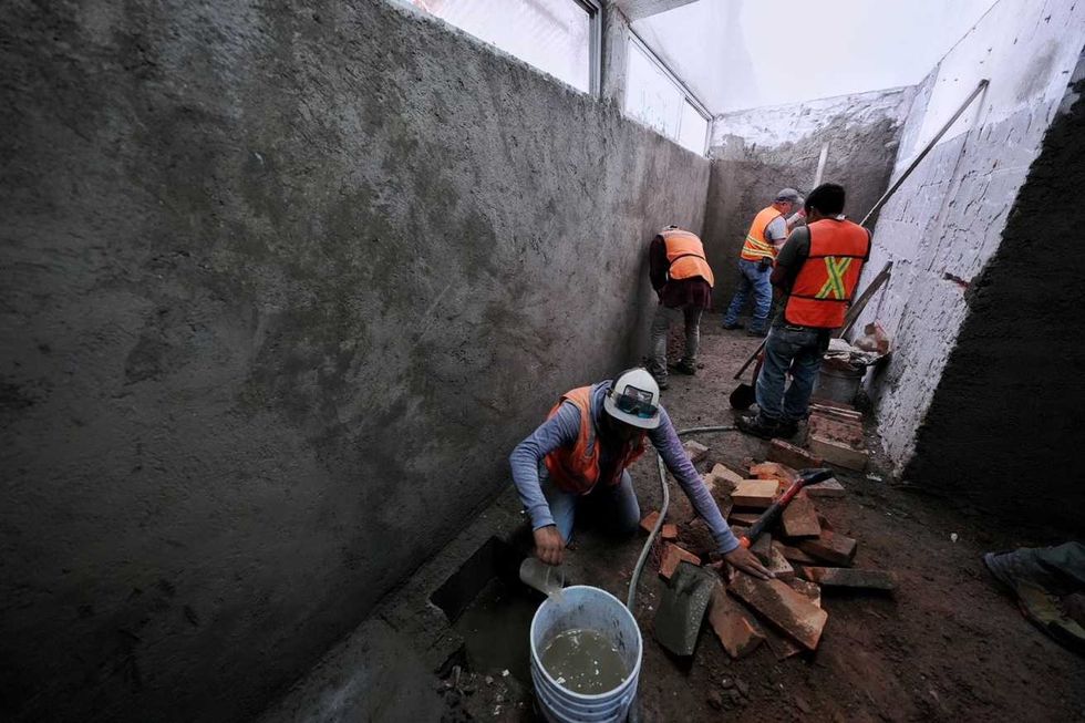 Trabajadores con chalecos reflejantes realizan labores de alba\u00f1iler\u00eda en un pasillo del mercado Escobedo