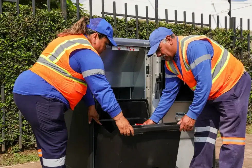 Trabajadores de Servicios P\u00fablicos muestran el contenedor interior de una papelera inteligente.