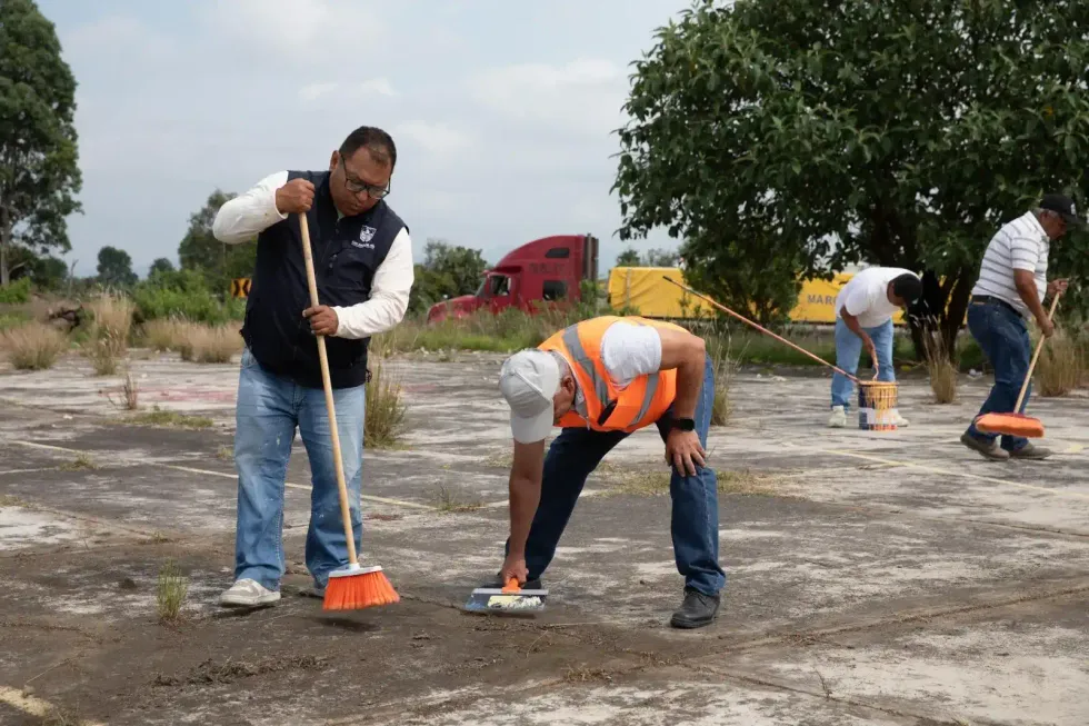 Trabajadores realizan labores de limpieza y pinta en una cancha