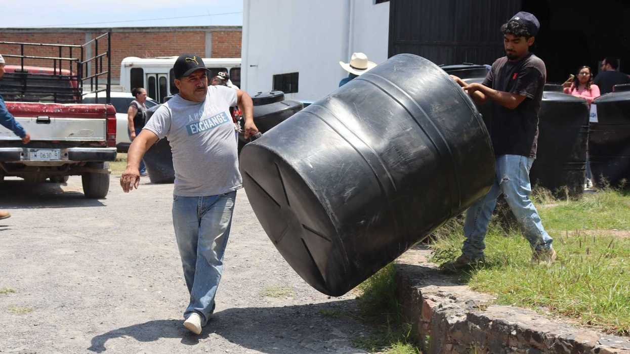 Trabajadores trasladan un tinaco durante la entrega de más de 170 unidades en San Juan del Río