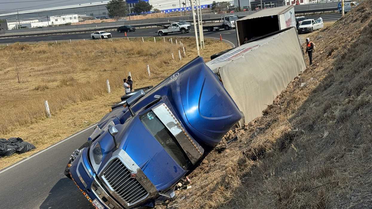 Tráiler tipo caja seca volcado sobre el talud del puente en la salida Calamanda de la autopista México-Querétaro en Pedro Escobedo