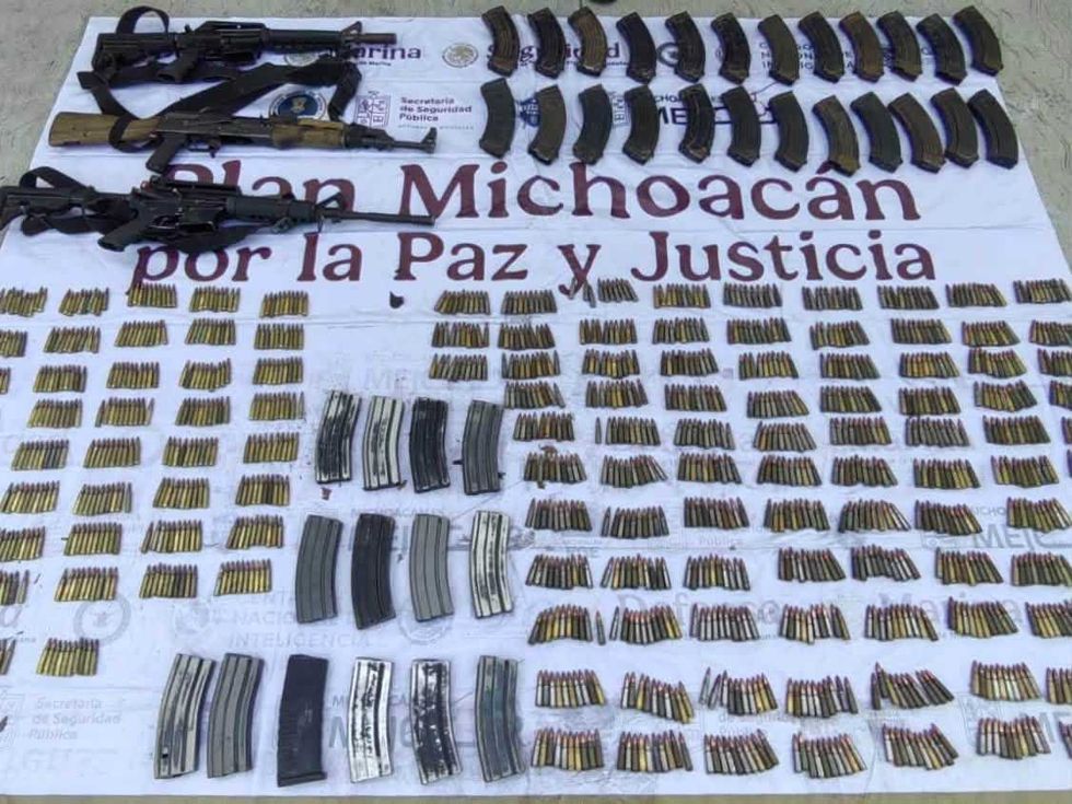 Tres fusiles de asalto y decenas de cargadores y cartuchos ordenados sobre una lona institucional