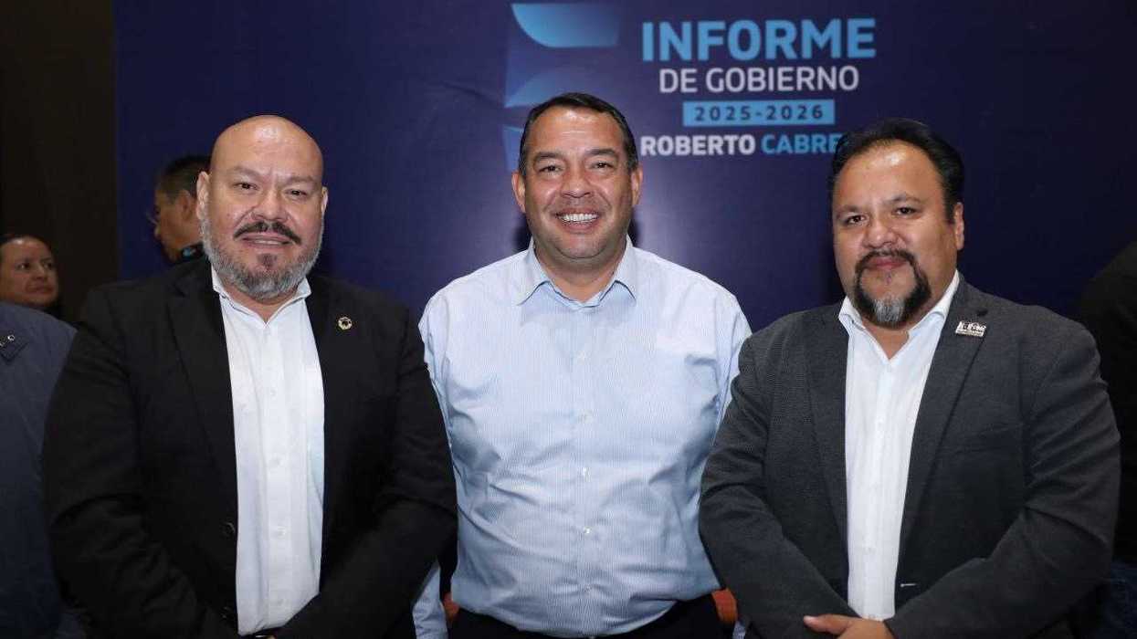 Tres hombres posan frente a una mampara del Informe de Gobierno durante el encuentro con industriales en San Juan del Río