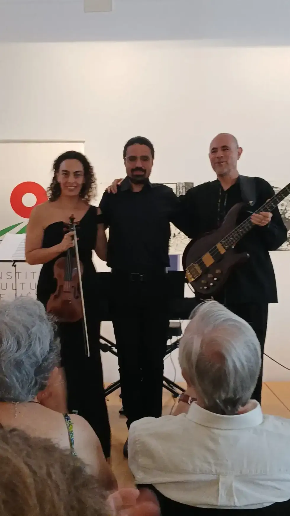 Tres m\u00fasicos posan ante el p\u00fablico en el Instituto Cultural de M\u00e9xico en Espa\u00f1a; la violinista porta su instrumento y el bajista su guitarra el\u00e9ctrica