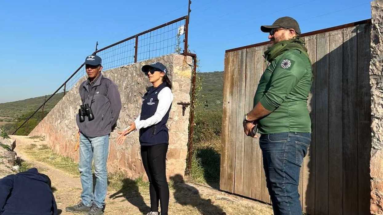 Tres personas conversan junto a una portada de piedra en terreno de área natural protegida en Querétaro