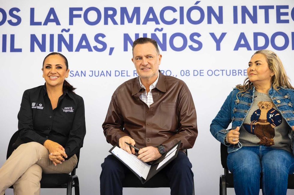 Tres personas sentadas en el pres\u00eddium durante la ceremonia de entrega del arcotecho en San Juan del R\u00edo