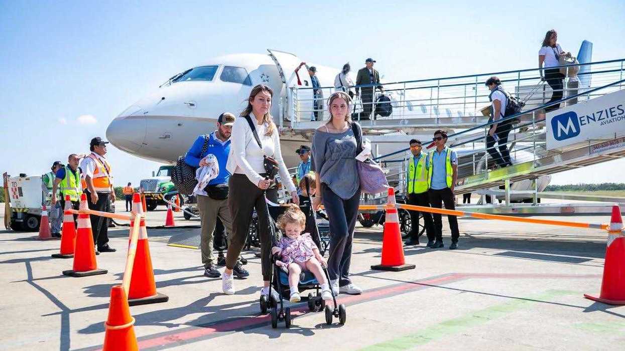 Turistas internacionales descienden de un avión por una escalinata en una pista aérea